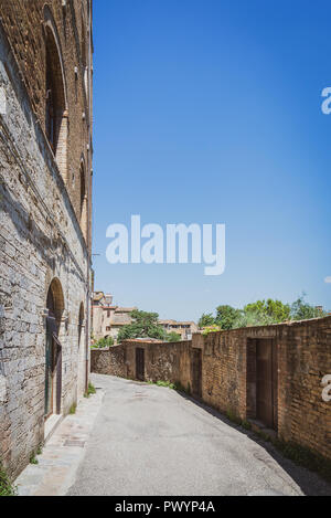 Vertikale Foto mit leeren Pflaster. Straße ist am Rande der Altstadt von San Gimignano. Die Stadt in der Toskana - Italien. Der Himmel über alte Gebäude ist cl Stockfoto