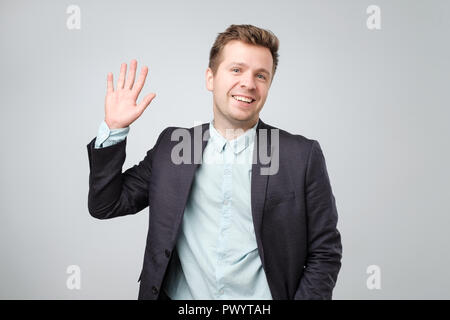 Attraktive europäische Studenten verzichtet auf Hand in hallo Geste während fröhlich lächelnd auf weißem Hintergrund isoliert. Stockfoto