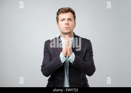 Porträt eines verzweifelten jungen Mann mit gefalteten Händen, um Hilfe zu bitten. Menschliche emotion Gesichtsausdruck Gefühle, Körpersprache Stockfoto