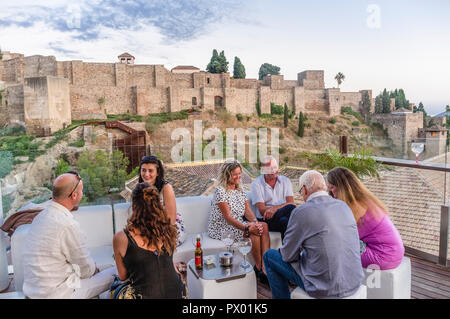 Menschen mit Alcazaba Burg im Hintergrund in der Lounge-Bar auf dem Dach der Alcazaba Premium Hostel, Malaga, Andalusien, Spanien. Stockfoto