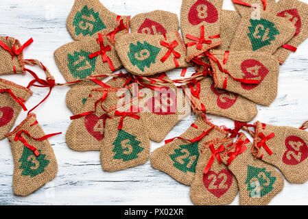 Adventskalender, ein Licht, Holz- Hintergrund liegen geflochtene Taschen mit Tage auf dem Kalender, freier Platz für Text Stockfoto