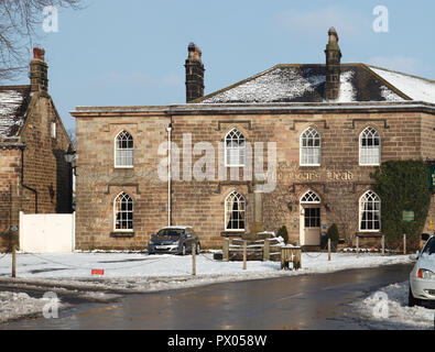 Snowy Winter Blick auf die Boars Head Hotel in Ripley in North Yorkshire, mit dem Kreuz und der Bestände vor dem Hotel Stockfoto