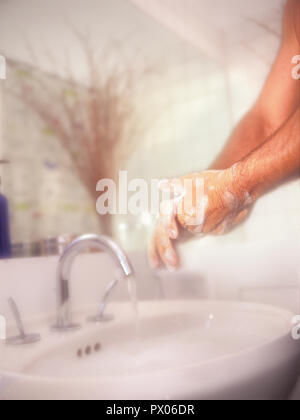 Man Wäsche und Waschen der Hände mit Nachdruck gegen ein weiches Hintergrund im Badezimmer Stockfoto