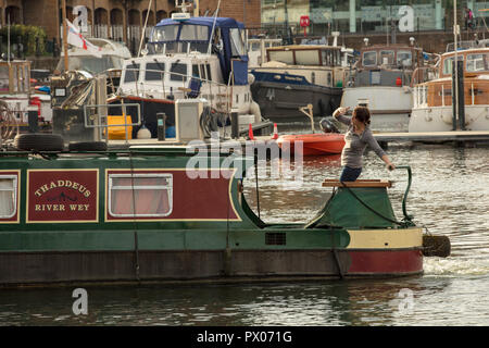 River Boat, gekonnt Lenkung durch die weibliche Skipper, auf den ruhigen Wassern der Limehouse Basin, London UK, immer bereit für einen neuen Liegeplatz Lage. Stockfoto