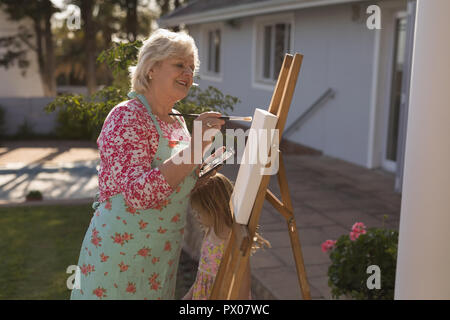 Ältere Frau Gemälde auf Leinwand im Garten Stockfoto