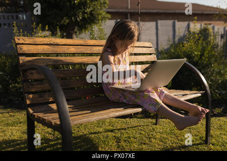 Mädchen mit Laptop im Garten Stockfoto