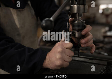 Schmied mit einer Presse Bohrer in der Werkstatt Stockfoto