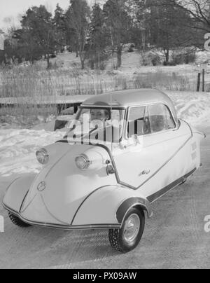 Fahren im Winter in den 1950er Jahren. Eine junge Frau führt das Deutsche microcar Messerschmitt KE 200. Ein 3 Rad kleine Auto mit genügend Raum, zwei Erwachsene und ein Kind im Auto zu passen. Das Auto wurde zwischen 1955-1964 hergestellt. Schweden 1955 Stockfoto