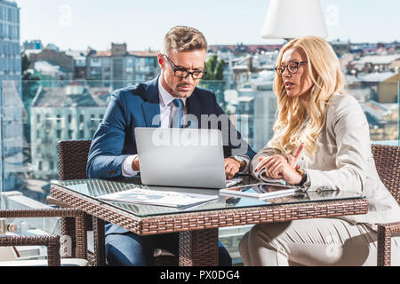 Zuversichtlich, dass Kollegen mit Laptop während der Sitzung im Cafe Stockfoto