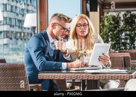Geschäftsleute auf Tablet besprechen sie bei der Arbeit während der Sitzung im Cafe Stockfoto