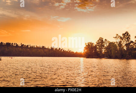 Große Sonne am Horizont leuchtet der See bei Sonnenuntergang Stockfoto