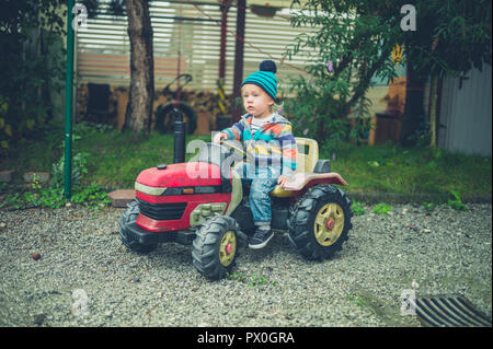 Ein kleines Kind reiten auf einem Spielzeug Traktor Stockfoto