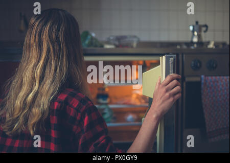 Eine junge Frau öffnet die Tür ihres Kühlschrank Stockfoto