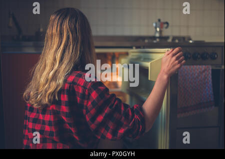 Eine junge Frau öffnet die Tür ihres Kühlschrank Stockfoto