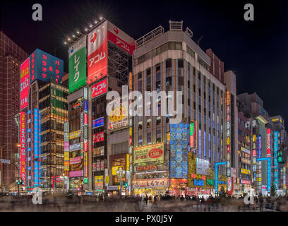 Ein Abend in der Nähe des geschäftigen Bahnhofs Shinjuku, Toyko, Japan an einer belebten Kreuzung, mit Leuchtreklamen, dem Einkaufsviertel, neon Reklametafel. Stockfoto