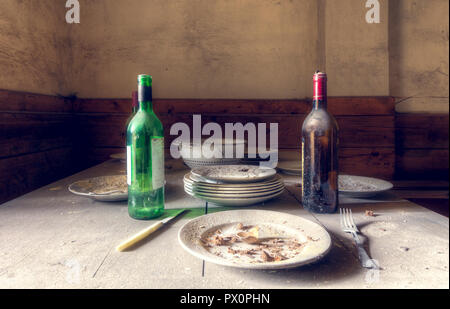 Nahaufnahme einer Tabelle mit Platten, Flaschen und hinter Essen in einer verlassenen Villa in Italien. Stockfoto