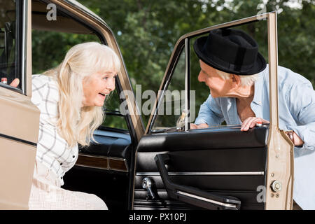 Lächelnd älterer Mann öffnen Auto Tür vor der Frau Stockfoto