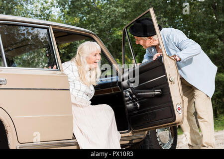 Ältere Menschen öffnen Auto Tür vor der schönen Frau Stockfoto