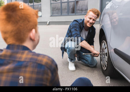 Vater Reifenwechsel im Auto mit radschlüssel und Sohn Stockfoto