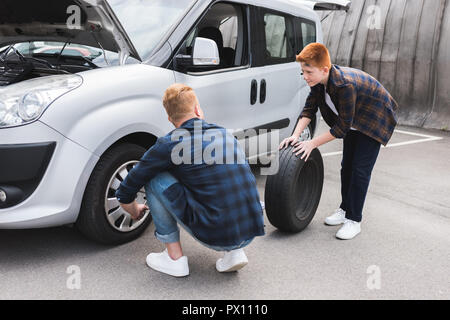 Vater und Sohn Reifenwechsel im Auto mit radschlüssel am Wochenende Stockfoto
