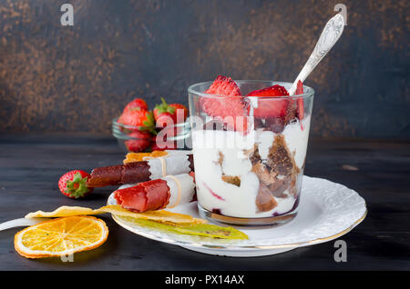 Schokolade Cookies, Sahne und Erdbeeren Nachtisch in einem Glas auf einem darkbackground, leckere Kleinigkeit, Kopie Raum Stockfoto