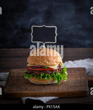 Hamburger mit Fleisch Patty und frisches Gemüse, eine leere Holz- Wegweiser nach oben einstellen Stockfoto