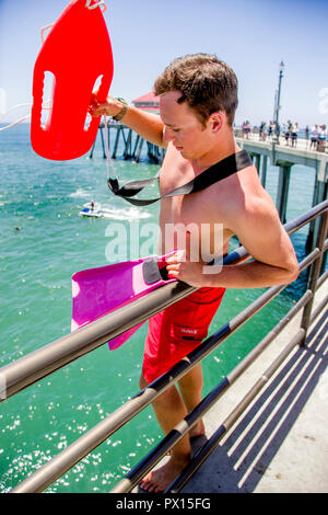 Schweben und Schwimmen flossen, ein Rettungsschwimmer bereitet die vom Pier in Huntington Beach, CA springen, um die Rettung eines ertrinkenden Opfer. Stockfoto