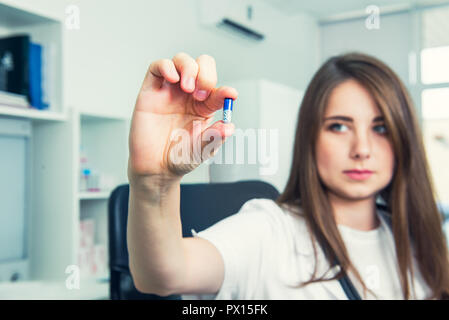 Ernst Ärztin im weißen Kittel mit Stethoskop Holding eine Pille zwischen den Fingern. Hand eines Krankenhauses medizinische Experte zeigt die Pille genommen zu werden. Stockfoto