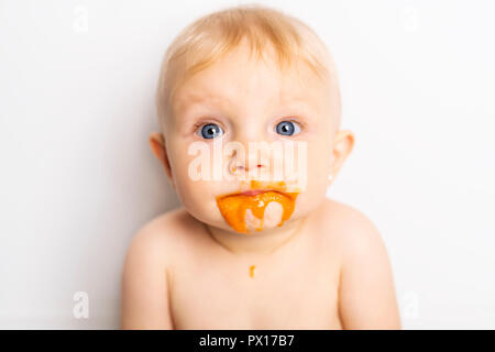 Ein Adorable Baby Mädchen, ein Durcheinander, während sich die Fütterung Stockfoto