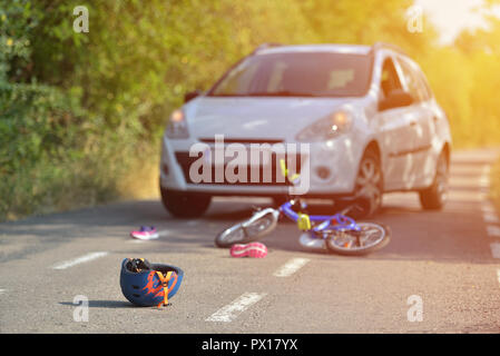 Nahaufnahme einer Radfahren Helm auf den Asphalt gefallen Neben einem Fahrrad nach Autounfall auf der Straße in der Stadt Stockfoto