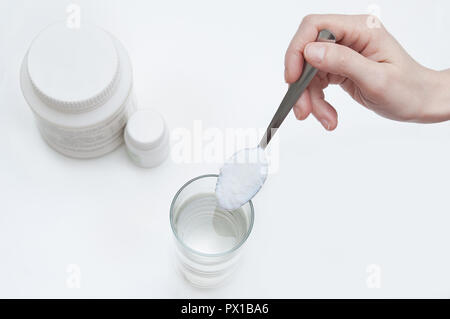 Pulver Absorptionsmittel auf einem Löffel in ein Glas mit Wasser. Close-up. Ansicht von oben Stockfoto