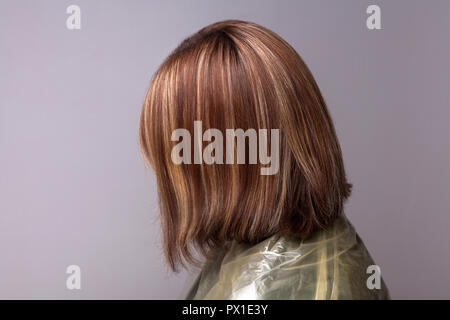 Profil Seitenansicht der Frau mit markierten braunen Haare. indoor Studio shot, auf grauem Hintergrund. Stockfoto