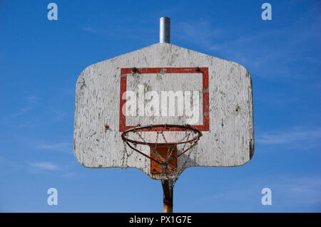 Nahaufnahme eines im Freien alte hölzerne Rückwand eines Metalls Basketballkorb mit gebrochenen metall kette Korb. Blauen Himmel im Hintergrund. Stockfoto