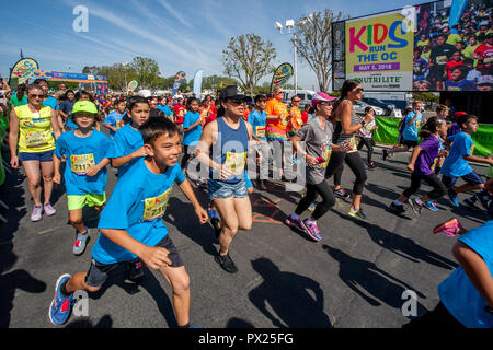 10-jährige multirassischen Läufer pass ein Jumbotron video Bild von sich selbst als das Rennen in einer Gemeinschaft Titel Event in Costa Mesa, CA beginnt. Stockfoto