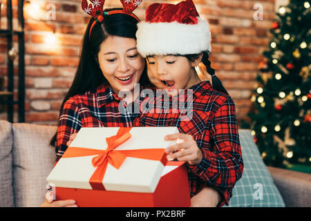 Eltern und Kind Spaß Eröffnung der Gegenwart von Online Shopping im Innenbereich auf Boxing Day. Öffnen Sie Geschenke Boxing Day Konzept. Weihnachten Kind in einem Stockfoto