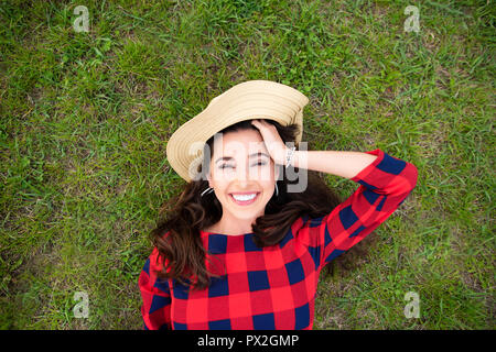 Eine schöne junge Frau ist Gefühl fröhlichen liegen auf dem Rasen im Park, Ansicht von oben. Stockfoto