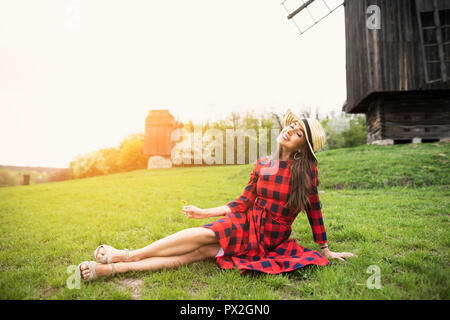 Schöne junge Frau, genießen das Wetter im Frühling beim Sitzen auf dem Rasen im Park Stockfoto