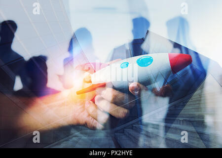 Geschäftsmann startet seine Start-up-Unternehmen. Hand mit einem Holz- Rakete. Double Exposure mit Lichteffekten Stockfoto