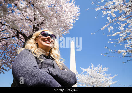 Blonde Frau wirft mit einem Gefühl von Erfolg und Erfüllung in der Nähe des Washington Monument mit Kirschblüten Bäume in voller Blüte. Stockfoto