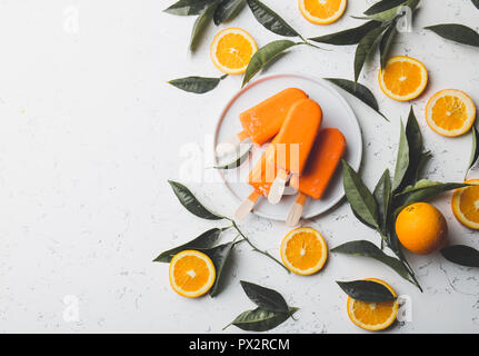 Flach orange Popsicle, frisch gepressten Obst- und Orange Tree Blätter, weiße Hintergrund. Stockfoto