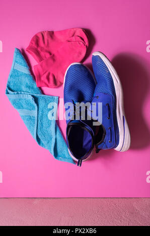Blue Sport Schuhe auf eine isolierte rosa Hintergrund, blau Handtuch für Sport Zubehör, Fitness Concept. . Schuss von oben, trendigen Kontrastfarben Stockfoto