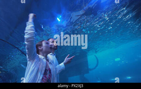 Junges Mädchen mit Vati amüsant beobachten die Fische im Aquarium Stockfoto