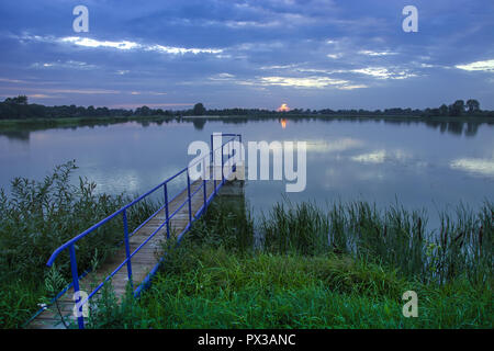 Die kleine Brücke über den See, Schilf und Wolken im Himmel Stockfoto