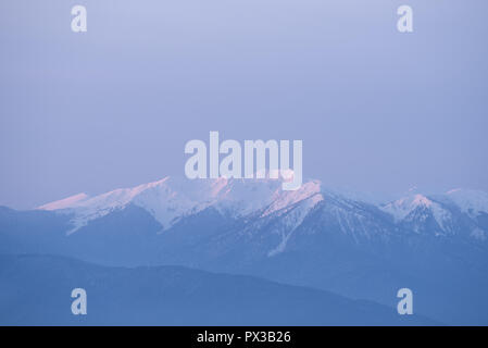 Blick auf Berg im Schnee. Winterlandschaft mit Morgendämmerung Sonnenlicht. Pastell Farben in der Natur Stockfoto