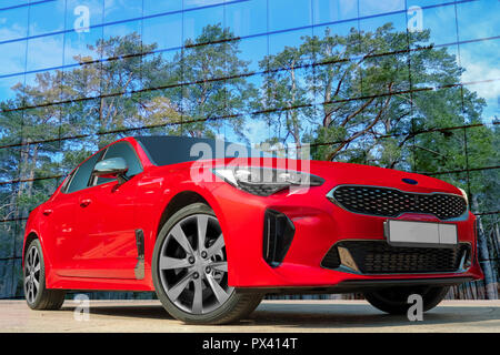 Rotes Auto auf einem Hintergrund der Kiefern. Stilvolles, modernes, helles Bild des Autos für Design Lösungen. Stockfoto