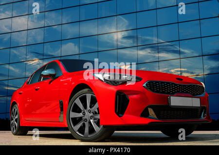 Rotes Auto vor dem Hintergrund des Abendhimmels. Stilvolles, modernes, helles Bild des Autos für Design Lösungen. Stockfoto
