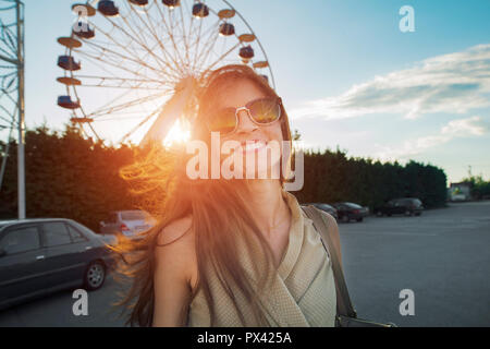 Frau fröhlich lächelnd vor einem Riesenrad Stockfoto