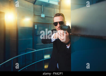 Leibwächter in Anzug und Sonnenbrille mit Gewehr in der Hand Stockfoto