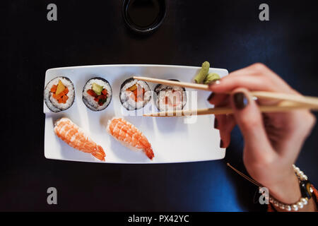 Nahaufnahme eines Sushi Platte mit weiblicher Hand mit Stäbchen Stockfoto