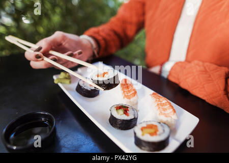 Nahaufnahme eines Sushi Platte mit weiblicher Hand mit Stäbchen Stockfoto